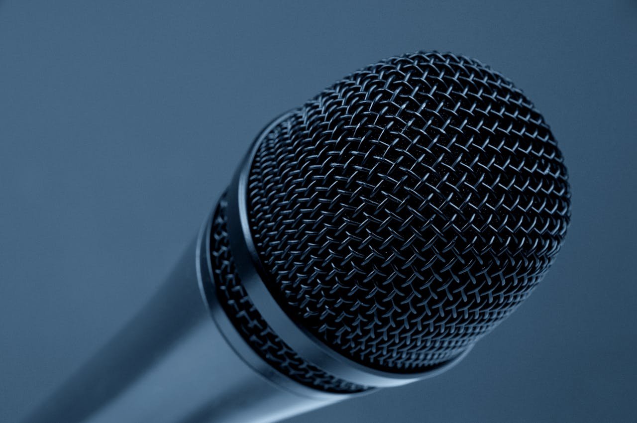 A detailed close-up of a microphone with a blue monochrome background, highlighting its intricate mesh design.