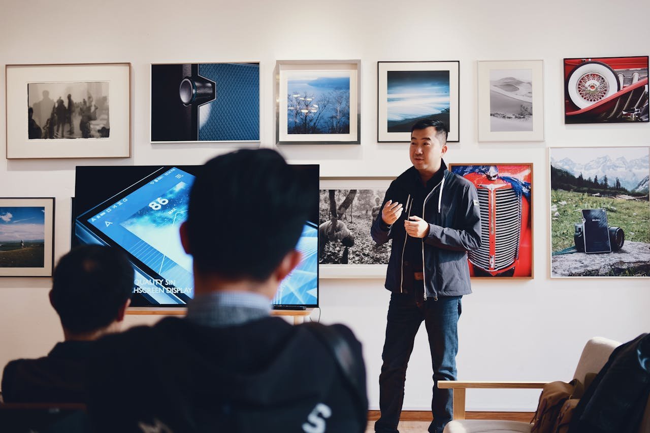 Man giving a presentation in a modern art gallery setting, engaging audience.